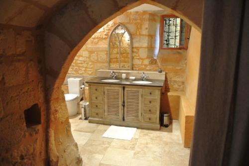 a stone bathroom with a sink and a mirror at Maison de la Combe in Domme