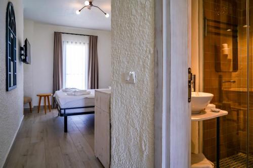 un bagno con lavandino e doccia e un letto di CEMAL ALAÇATI BUTİK HOTEL ad Alaçatı
