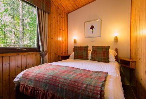 een slaapkamer met een bed in een kamer met een raam bij Macdonald Lochanhully Resort in Carrbridge