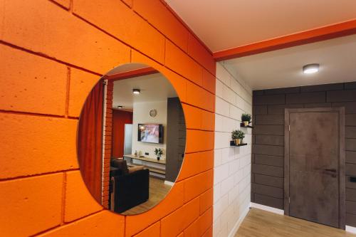 een oranje bakstenen muur in een kamer met een spiegel bij Apart Lux Loft Panorama in Sumy