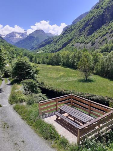 un banco de madera sentado en un camino junto a una montaña en la fario, en Gavarnie