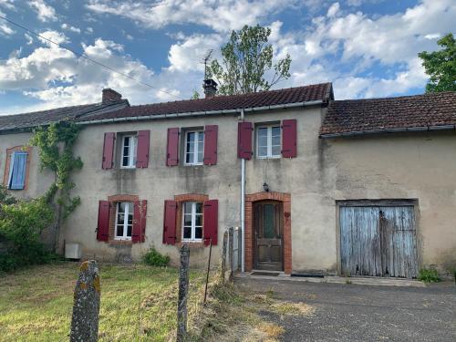 ein altes Haus mit roten Rollläden drauf in der Unterkunft La Maison de Gaston in Saint-Cirgue