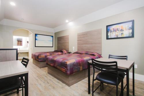 ヒューストンにあるPalace Inn Beltway 8 & Westviewのベッド2台とテーブルと椅子があるホテルの部屋