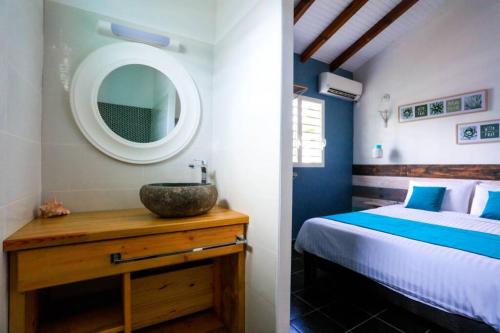 a bedroom with a bed with a sink and a mirror at Aigue-marine in Sainte-Anne