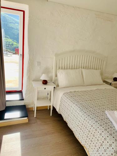 a white bedroom with a bed and a window at Terraços do Távora in Tabuaço
