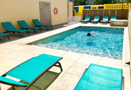 Karaibes Residence في لو جوسيير: شخص يسبح في مسبح والكراسي الزرقاء