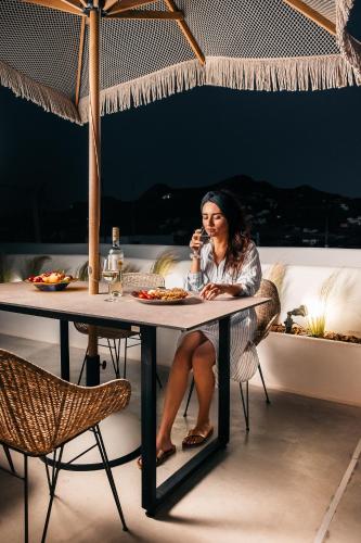a woman sitting at a table talking on a cell phone at Emery Hotel in Naxos Chora