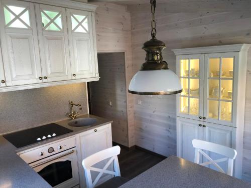 une cuisine avec des placards blancs et une lampe pendant dans l'établissement Heritage House Nida with 2 Bedrooms & Free Parking, à Nido