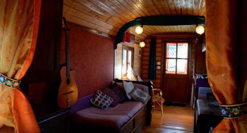 a living room with a couch and a guitar at La Roulotte de la Fay in Dompierre-les-Ormes