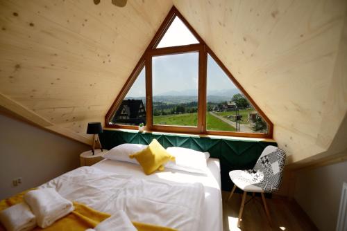 a bed in a room with a large window at Dom Wczasowy Tatrzański in Szaflary