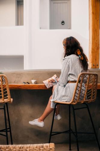 a woman sitting at a table reading a book at Emery Hotel in Naxos Chora