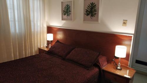 ein Schlafzimmer mit einem Bett und zwei Lampen an Tischen in der Unterkunft Playa Grande in Piriápolis