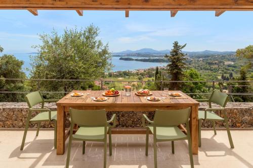 a wooden table and chairs on a patio with a view at Greenstone Villas Corfu - Luxury Sea View Villas in Pyrgi