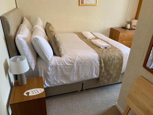 a bedroom with a bed with white sheets and pillows at Sharn Bek Hotel in Blackpool