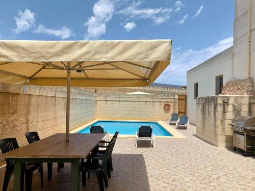 a patio with a table with an umbrella and a swimming pool at Andar Farmhouse in Victoria
