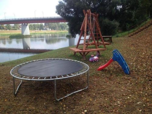 a trampoline and a swing set next to a river at Pirtis Prie Neries Jonava in Jonava