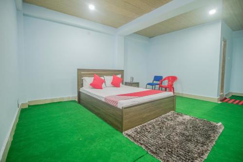 Schlafzimmer mit einem Bett mit roten Kissen und grünem Teppich in der Unterkunft OYO Brikcha Mukhia Home Stay in Pelling