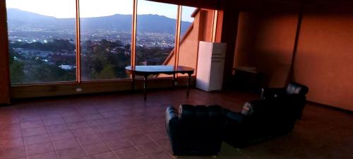 a room with two chairs and a table and windows at Hotel Monte Campana Escazu in San José