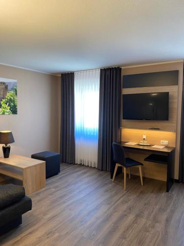 een hotelkamer met een bureau en een televisie bij FETZ DAS LORELEY HOTEL in Dörscheid