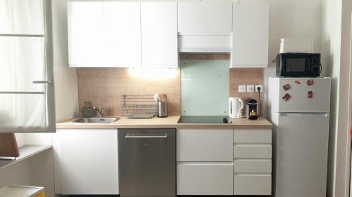 une cuisine avec des armoires blanches et un réfrigérateur blanc dans l'établissement Appt 2 chambres au centre ville 4è, à Marseille