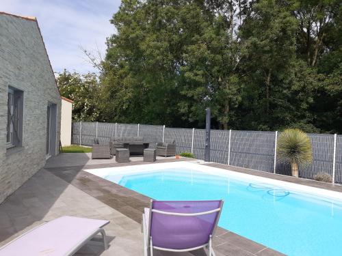 een zwembad met een paarse stoel en een tafel bij Chambre d'hôte la coccinelle in Meschers-sur-Gironde