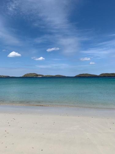 a beach with blue water and islands in the background at 1 Anderson Court in Stornoway