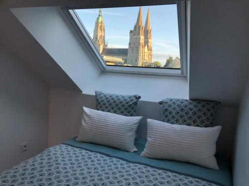 uma cama com duas almofadas num quarto com uma janela em Nouveau ! Appartement loft hyper centre Bayeux em Bayeux