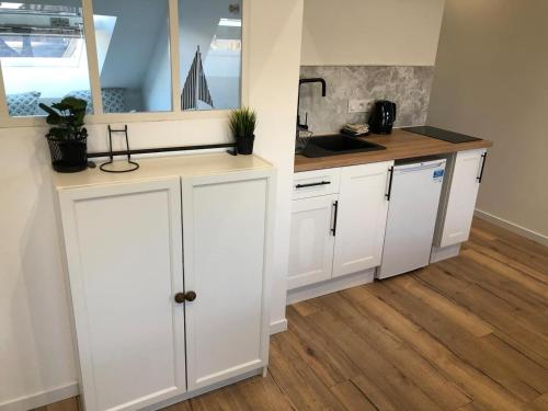 a kitchen with white cabinets and a wooden floor at Nouveau ! Appartement loft hyper centre Bayeux in Bayeux