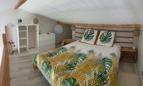een slaapkamer met een bed met tropische kussens bij Moments de détente. in Carsan