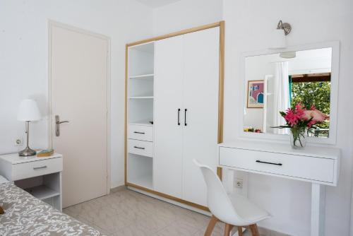 a white bedroom with a mirror and a white chair at Averto Corfu Apartments in Dassia