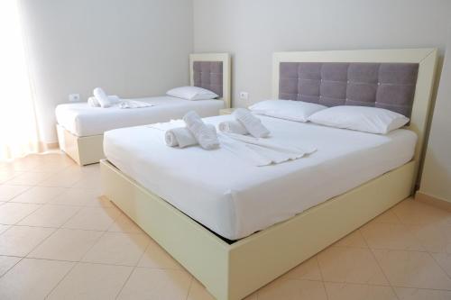 two beds in a hotel room with white sheets at Vila Balani in Ksamil