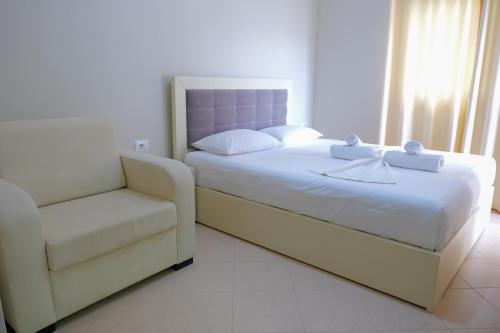 a bedroom with a large bed and a chair at Vila Balani in Ksamil
