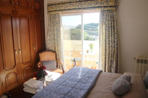 a bedroom with a bed and a window and a chair at Castelinho Carrascal Sintra Summer Apt & Heated Pool in Sintra