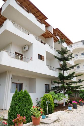 an apartment building with a pine tree in the courtyard at Vila Balani in Ksamil