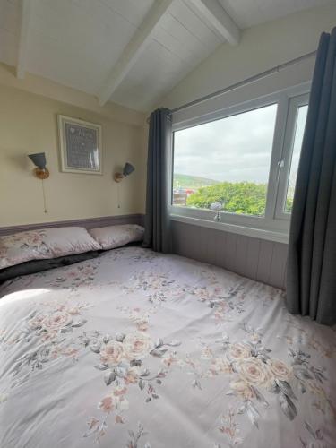 a bedroom with a bed with a large window at Kevara Shepherds Hut in Finstown