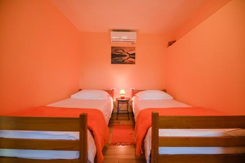 Dos camas en una habitación con paredes naranjas. en Villa Brbon - Serene Getaway, en Krbune