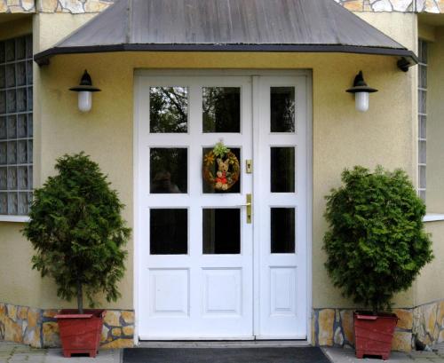 a white door on a house with two potted plants at Hegyesi Vendégház in Gödöllő