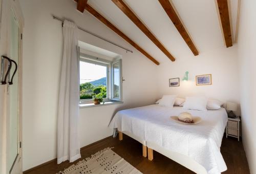 um quarto branco com uma cama com um chapéu em Golden Summerhouse em Komiža