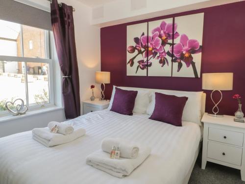 ReightonにあるWhite Rose Apartmentの紫の壁のベッドルーム1室(白い大型ベッド1台付)