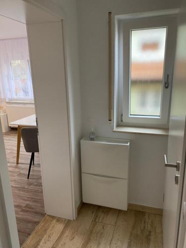 uma pequena cozinha branca com uma janela e uma mesa em Business-Apartment Braun em Abstatt