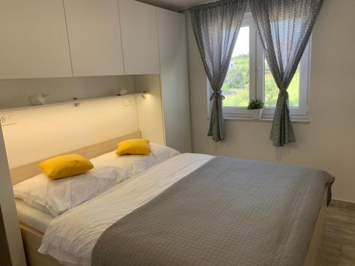 a bedroom with a bed with yellow pillows and a window at Apartments Lucie in Biograd na Moru