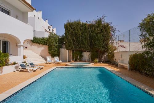 a swimming pool with chairs and a house at Apartments in Albufeira - Old Town in Albufeira