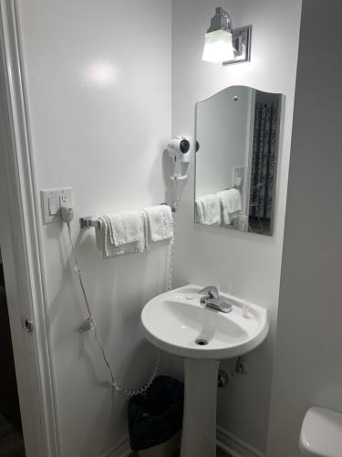 ein weißes Badezimmer mit einem Waschbecken und einem Spiegel in der Unterkunft Nites Inn Motel in Cornwall