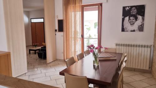 a dining room with a table with a vase of flowers on it at Villa Vittoria in Mesagne
