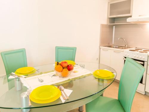 a glass table with yellow plates and a bowl of fruit at Green Home Apartments in Kotor