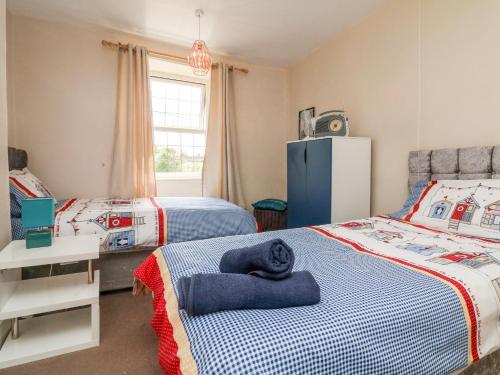 a bedroom with two beds and a blue refrigerator at Tea Cosy Cottage in Bude