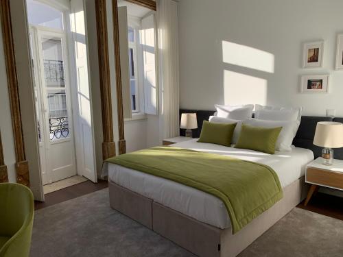 a bedroom with a large white bed with green sheets at Pharmacia GuestHouse in Coimbra