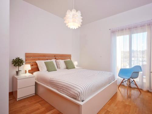 アルブフェイラにあるApartment Orada Marinaの白いベッドルーム(ベッド1台、青い椅子付)