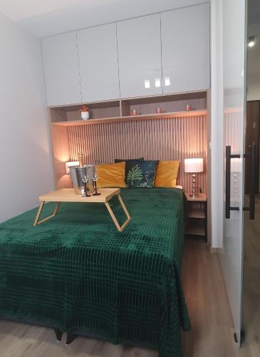sypialnia z zielonym łóżkiem i stołem w obiekcie Apartament Green Diamond Rakowicka w Krakowie