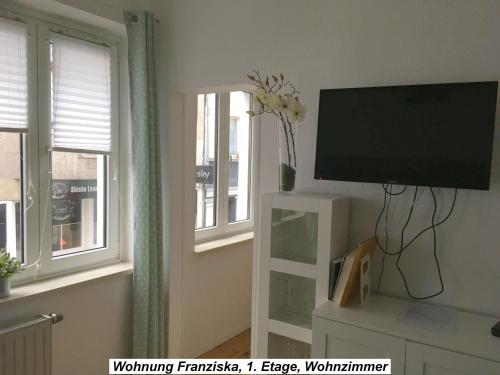 a living room with a flat screen tv and two windows at Ferienwohnung im Herzen der Koblenzer Altstadt in Koblenz
